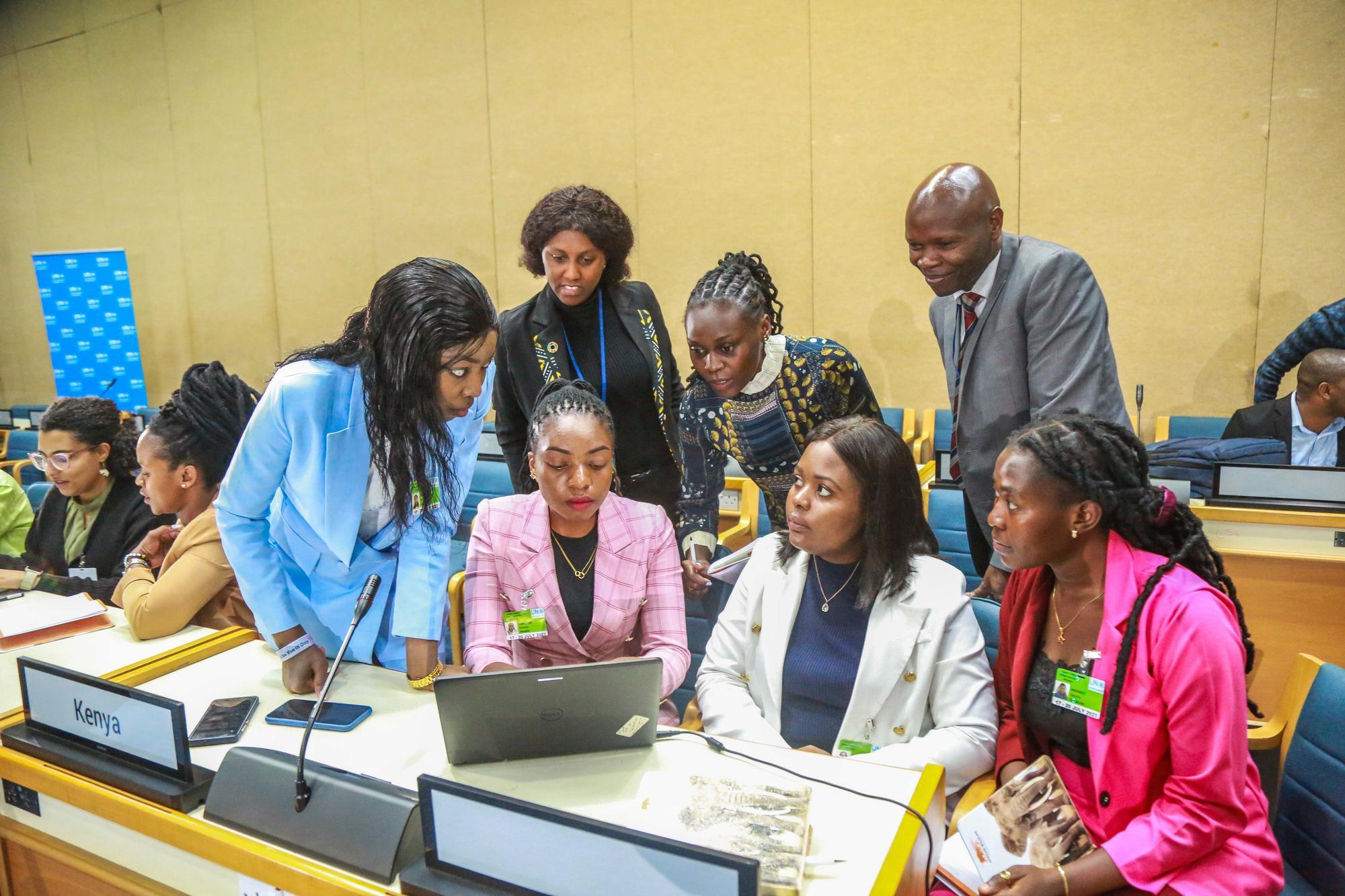 A group of policy experts convene at a computer
