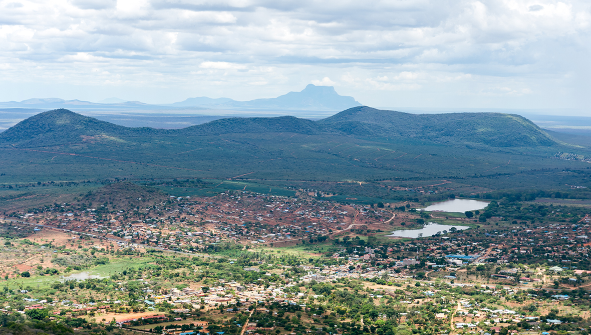 An aerial shot of a mountainous, green landscape with residences.