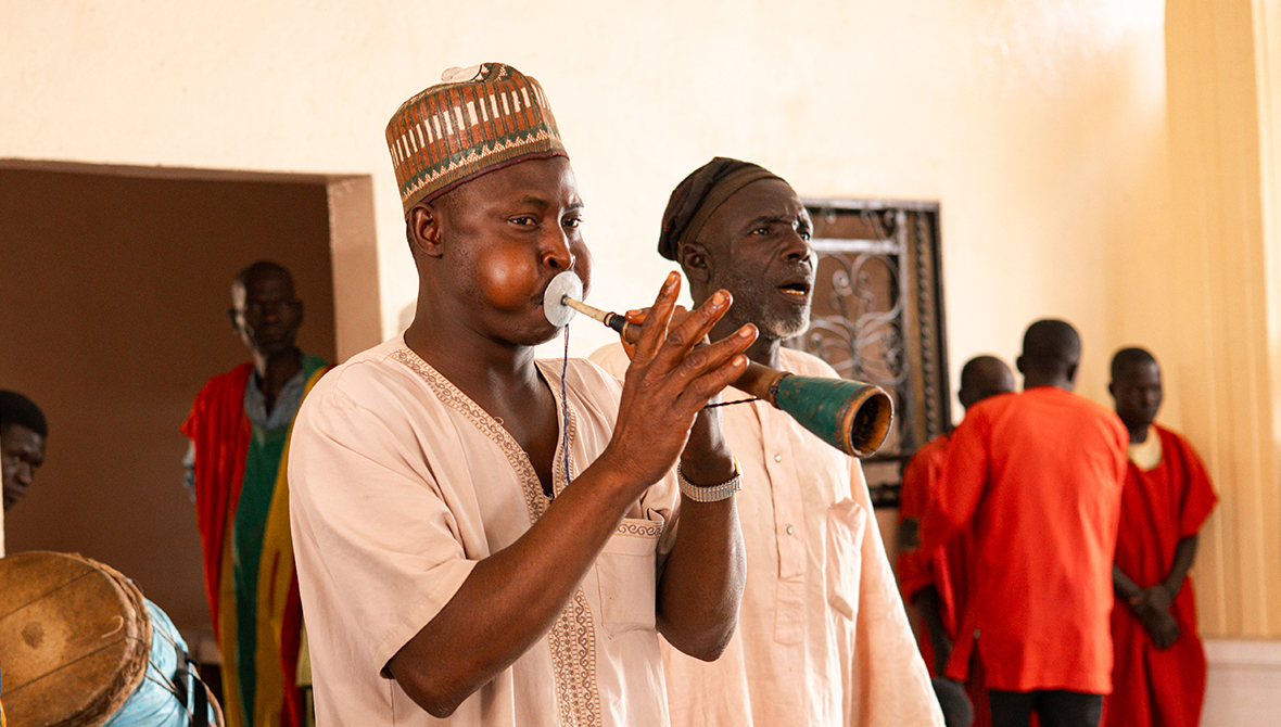 An usher blasts a trumpet.