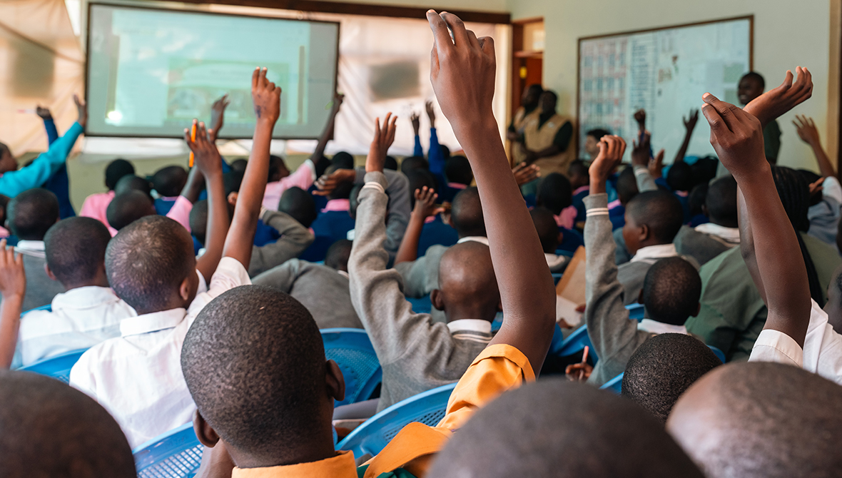 Students raise their hands in a classroom.
