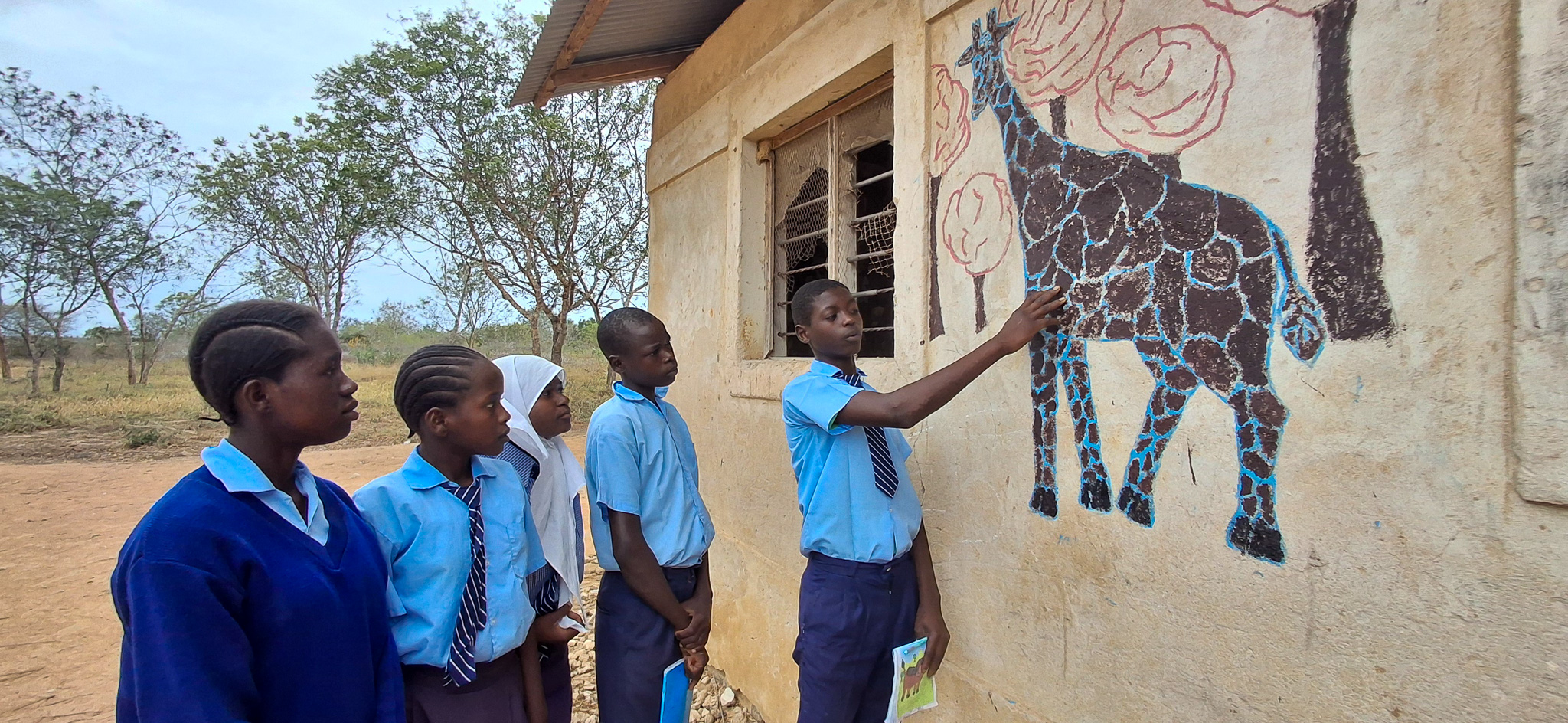 Bakari showing his classmates some of his artwork.