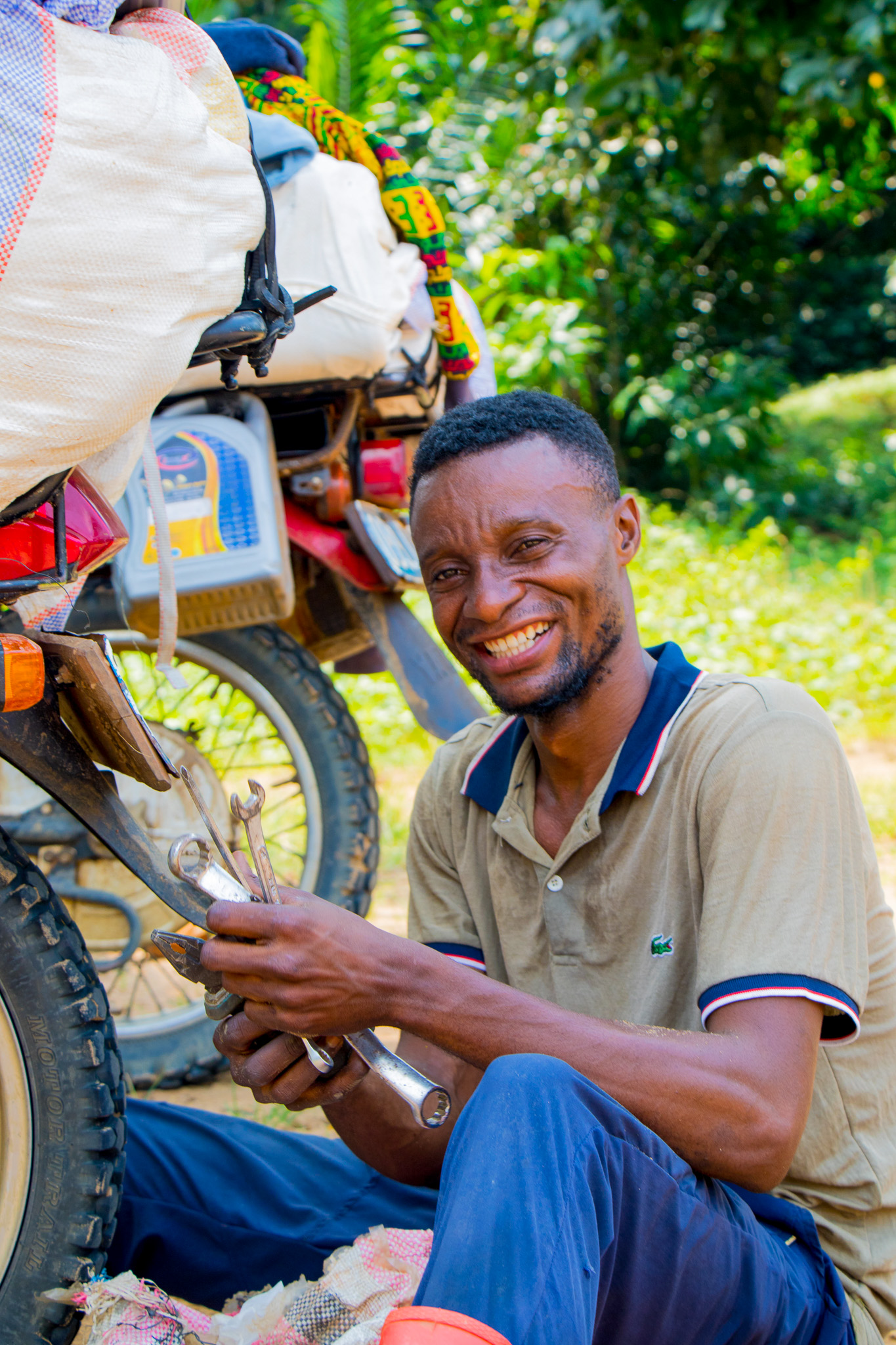 Jeancy Luaka joyfully prepares his motorcycle for another trip through the dense forest. 