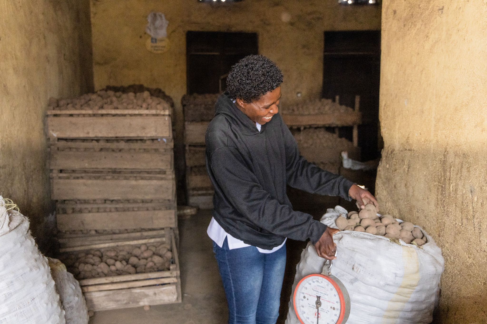 Agnes weighs sacks of Irish potatoes in her storage space.