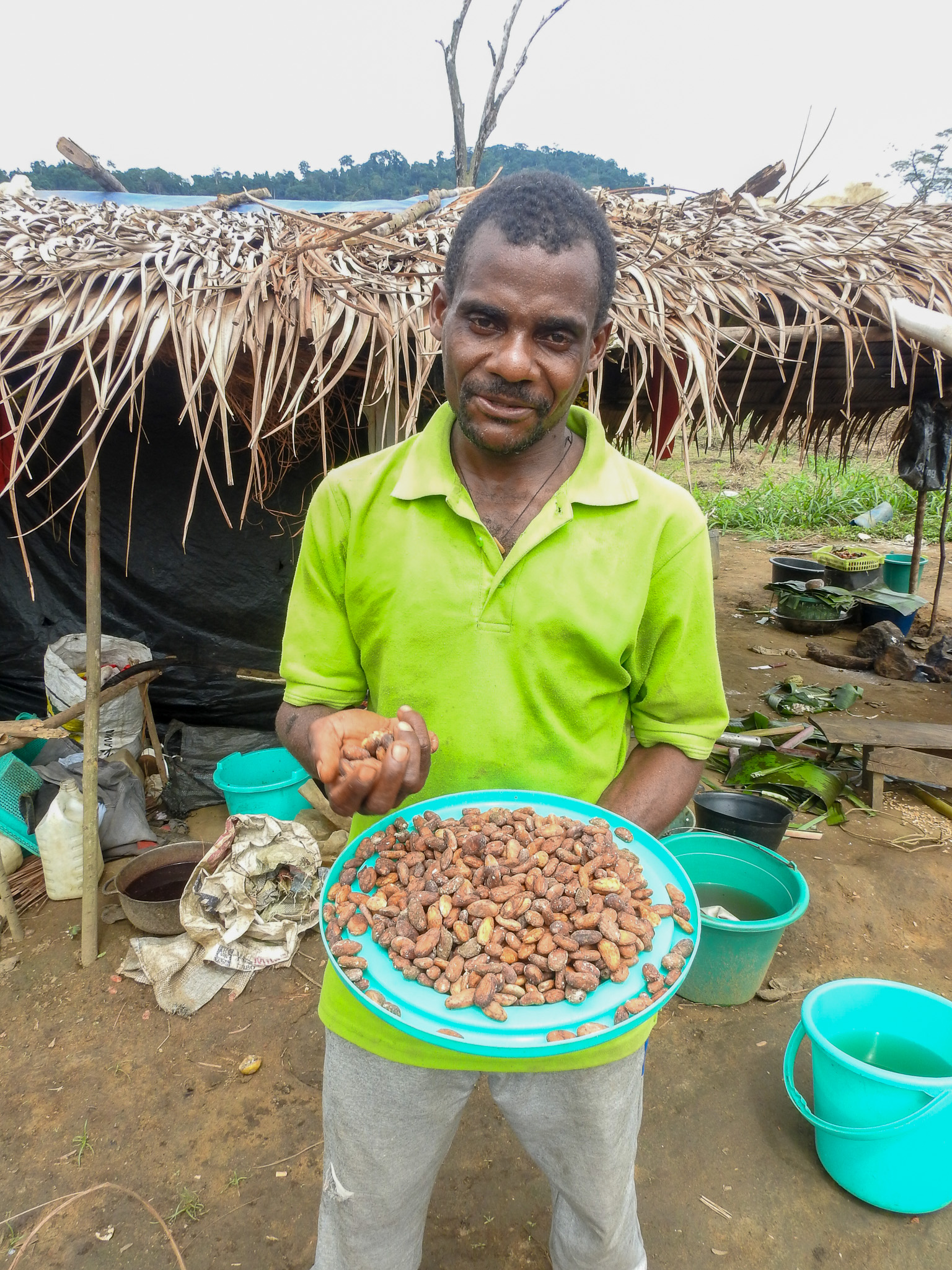 Jean Daniel stands in front of his home holding cocoa seeds which he was able to harvest from his cocoa farm for the first time. 