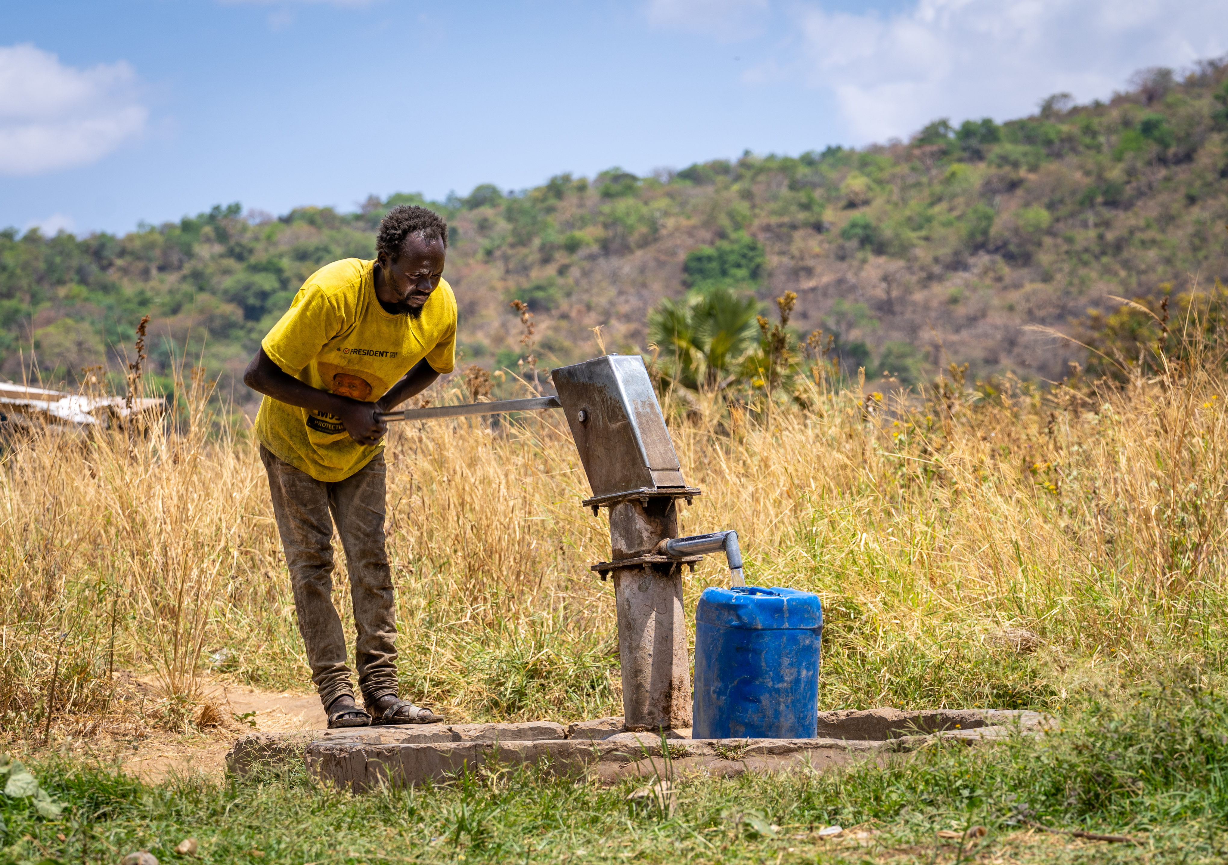A community member retrieves water from a borehole pump in Kidepo landscape, Uganda.