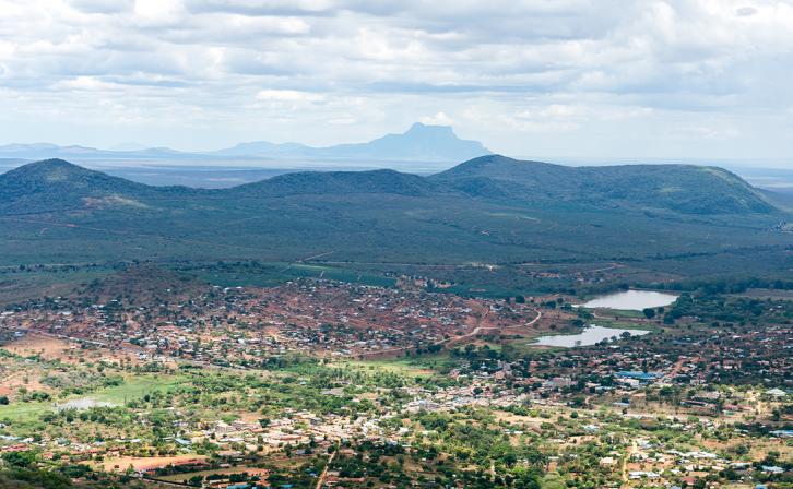 An aerial shot of a mountainous, green landscape with residences.