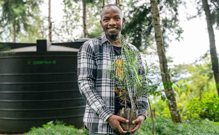 Eliud Mwasingo Kimori holding one of his seedlings in his thriving tree nursery .