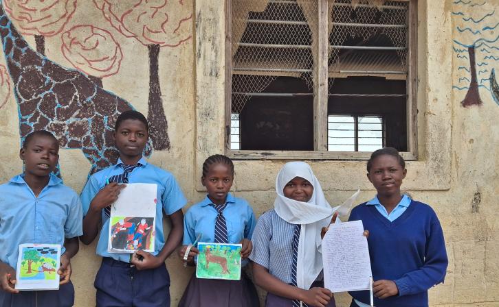Bakari Ali Mangale (second from left) and his classmates stand alongside his artwork.